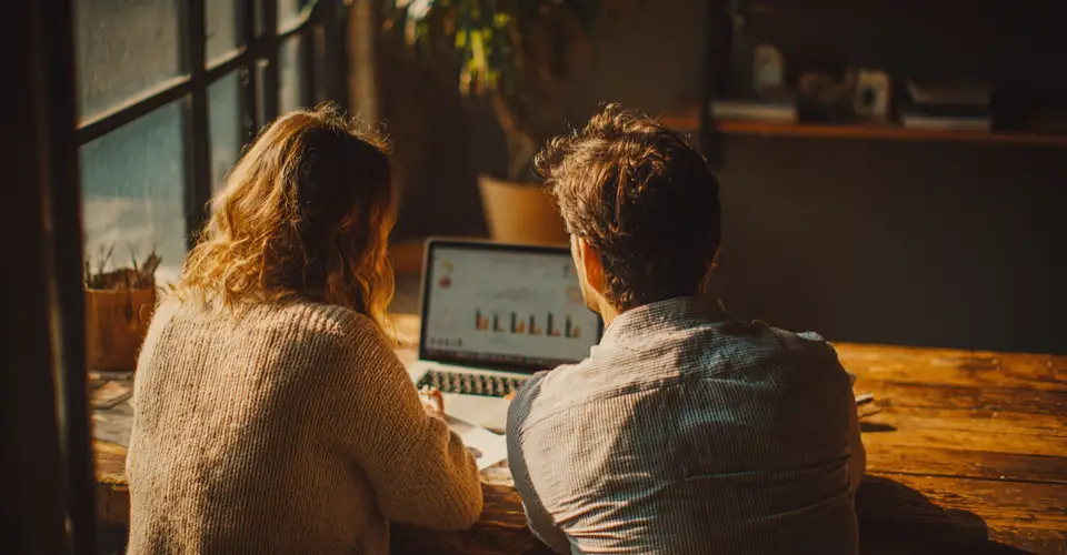 Small business owner and consultant reviewing website pages and analytics together at a table.