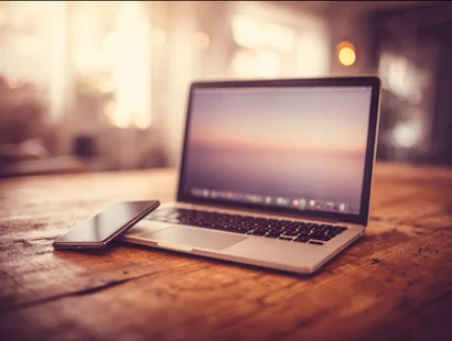 Laptop and smartphone on a wooden table symbolizing a fast, secure small business website across devices.